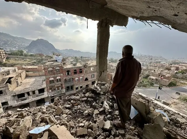 رجل يقف على منزل مدمر