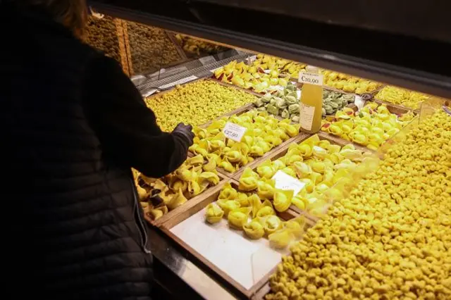 Taze makarnalar tezgahta satılıyor, bir kadın onlara uzanmış.