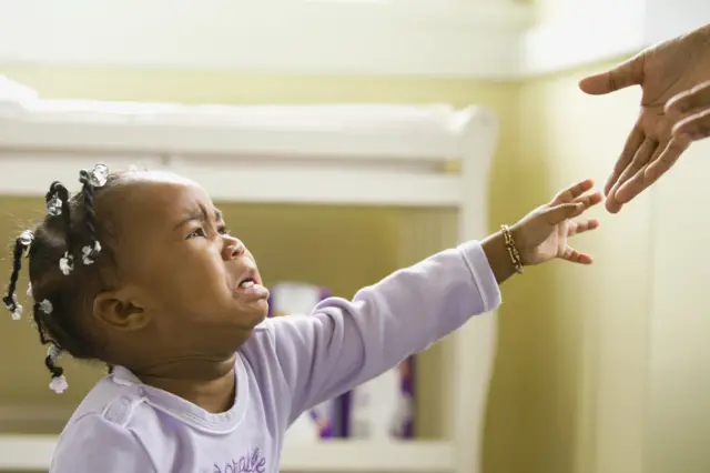 Une fille pleure et tend la main vers un adulte
