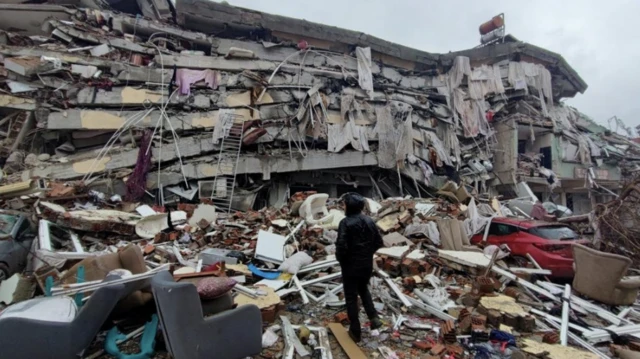 Seorang pria berdiri di depan bangunan yang runtuh setelah gempa bumi di Kahramanmaras, Turki, 6 Februari 2023