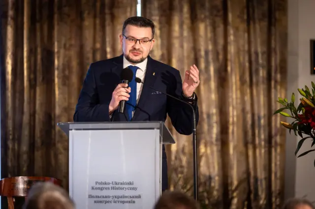 Алферов в костюме за трибуной