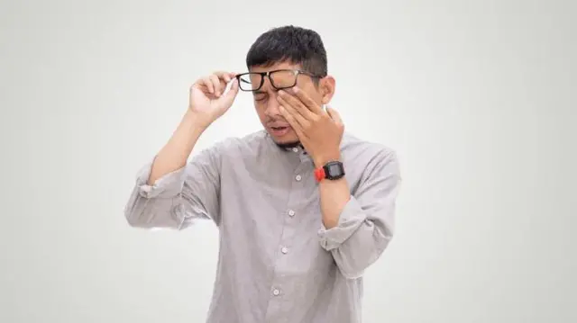 এক ব্যক্তি এক হাতে চশমা তুলে আরেক হাতে চোখ ধরে আছেন।