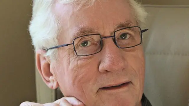 Frans de Waal sorrindo contidamente e olhando para câmera