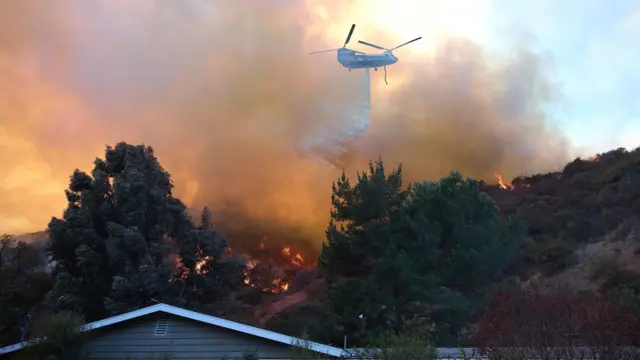 Los Angeles'taki yangını söndürmek için su döken bir helikopter