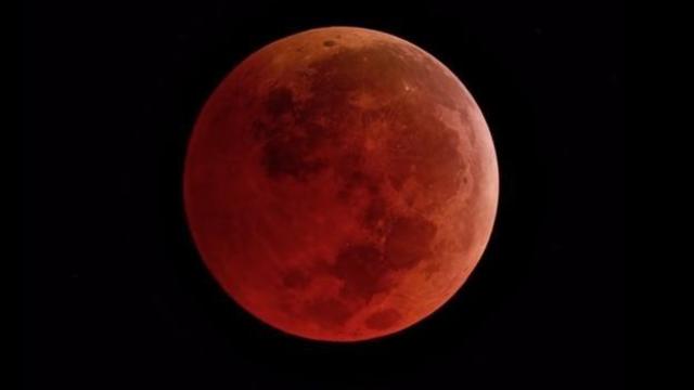 During a total lunar eclipse, sunlight is filtered by the Earth's atmosphere and the Moon takes an orange hue