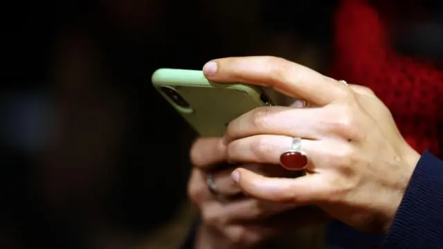 मोबाइल फोन चलाउँदै गरेका एक व्यक्तिका हात