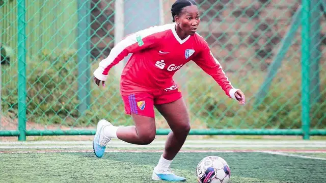 Kenya women's football player, Esse Akida in red kit with the ball at her feet readying for a pass during a training session at an artificial football pitch in Nairobi