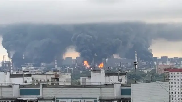Densas colunas de fumaça, acompanhadas por chamas, se elevam de uma refinaria de petróleo em Moscou