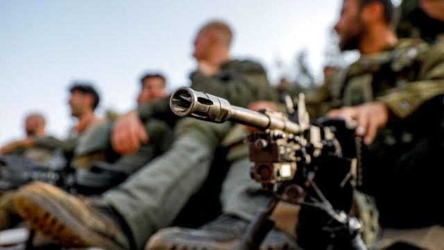 Un soldado del ejército israelí sentado junto a una ametralladora desplegada sobre un trípode en una posición en la región de la Alta Galilea en el norte de Israel, cerca de la frontera con Líbano, el 28 de octubre de 2023