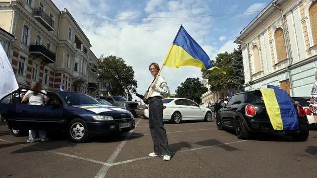 Женщина с украинским флагом на дороге на фоне машин, Одесса