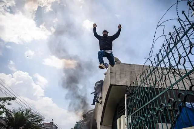 నేపాల్ పార్లమెంట్ బిల్డింగ్ ఎంట్రన్స్ వాల్ మీద నుంచి దూకుతున్న ప్రదర్శనకారుడు.