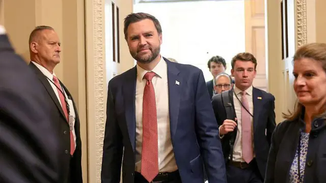 El vicepresidente JD Vance camina vestido de traje y sonriendo
