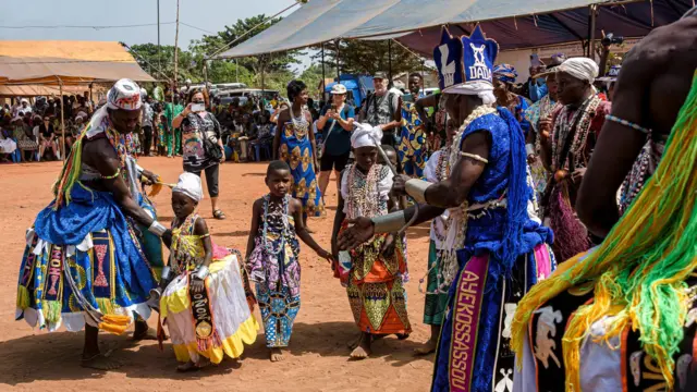 वूडू उत्सव के दौरान पारंपरिक पोशाक में लोग