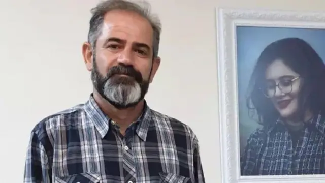 امجد امینی در کنار عکس دخترش مهسا (ژینا) امینی