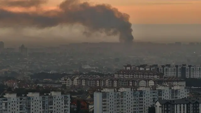 Дым от ракетного удара по Киеву поднимается над жилыми кварталами на фоне рассвет