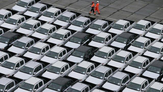 Workers walk past new Chinese cars unloaded from a ship at a commercial port in Vladivostok, Russia 