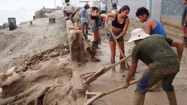 Pessoas limpando a lama após inundação ligada ao El Niño no Peru