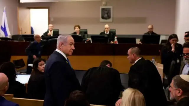 تصویری از جریان محاکمه نتانیاهو در اسرائیل. شمار زیادی از جمله هیئت قضایی و نتانیاهو در تصویر دیده می‌شوند.