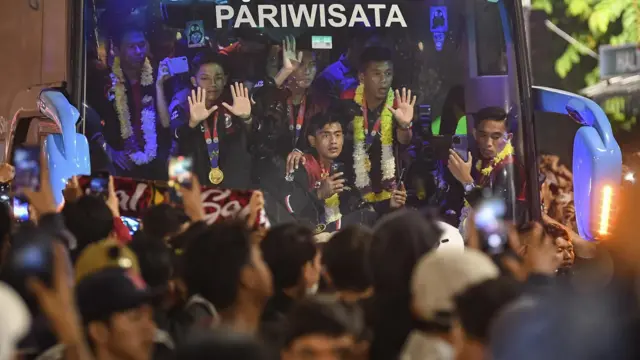 Sejumlah pesepak bola Timnas Indonesia U-22 melambaikan tangan ke arah suporter dari dalam bus di kawasan jalan Asia Afrika, Jakarta, Kamis (18/5/2023).