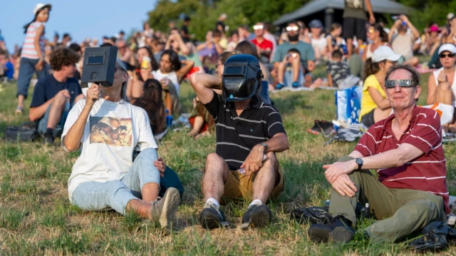 Ljudi sa maskama gledaju u Sunce