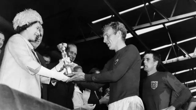 ਬ੍ਰਿਟੇਨ ਦੇ ਮਹਾਰਾਣੀ ਐਲਿਜ਼ਾਬੈਥ ਇੰਗਲੈਂਡ ਦੀ ਕੌਮੀ ਫੁਟਬਾਲ ਟੀਮ ਦੇ ਕਪਤਾਨ ਬੌਬੀ ਮੂਰ ਨੂੰ ਜੂਲਸ ਰਿਮੇਟ ਕੱਪ ਭੇਟ ਕਰਦੇ ਹੋਏ