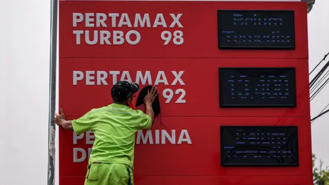 Petugas SPBU sedang membersihkan papan penampang harga bahan bakar minyak di SPBU Pertamina. 