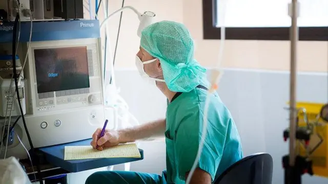 Dokter anestesi mencatat tanda-tanda vital pasien.