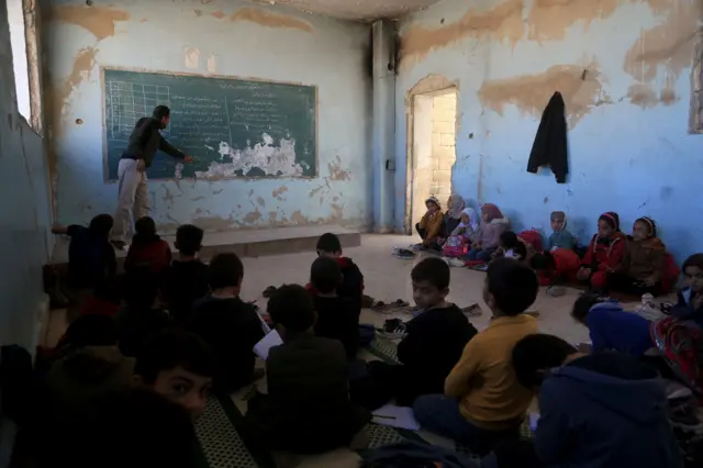16 Ekim'de İdlib'te duvarları hasarlı, masaları, kapıları ve pencereleri eksik bir sınıfta eğitim gören Suriyeli çocuklar.