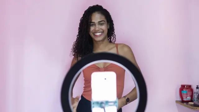 स्मार्टफोनको क्यामराबाट फोटो खिचाउँदै एक युवती 