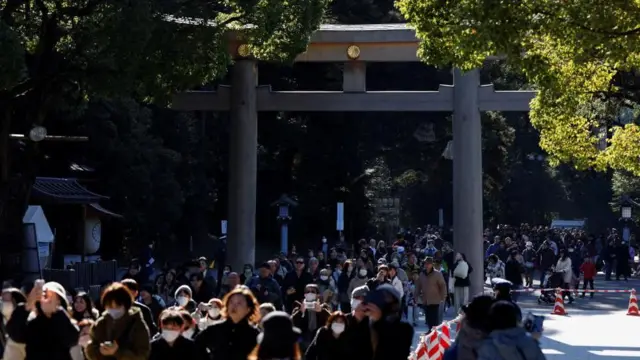 木々に囲まれた大きい鳥居を、次々と参拝客がくぐっている