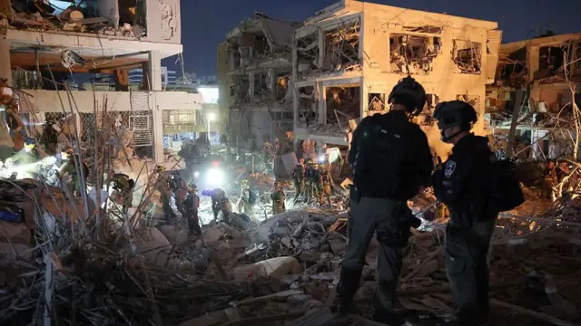 Petugas mencari di antara puing-puing bangunan setelah serangan rudal Iran di kota Bat Yam, Israel, sebelah selatan Tel Aviv, pada dini hari tanggal 15 Juni 2025. Sirene dan ledakan serangan udara terdengar di Yerusalem dan Tel Aviv pada dini hari tanggal 15 Juni, kata wartawan AFP, saat Israel dan Iran saling tembak untuk hari ketiga. 