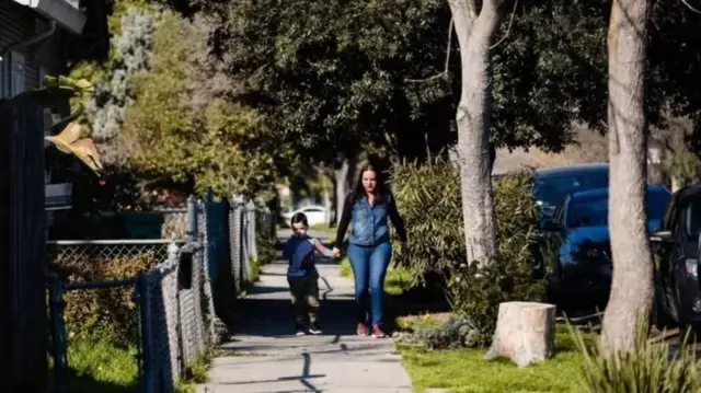 Une femme marchant avec un enfant sur une allée.