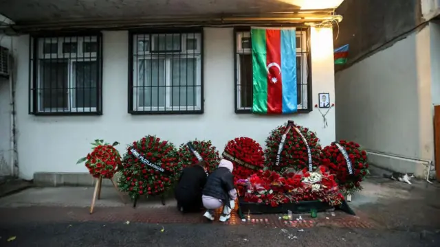 Una mujer enciende velas en la pared de un edificio de apartamentos en memoria del piloto Alexander Kalyanin, una de las víctimas que murieron en el accidente del Embraer 190 de Azerbaijan Airlines cerca del aeropuerto de Aktau, en Kazajstán,
