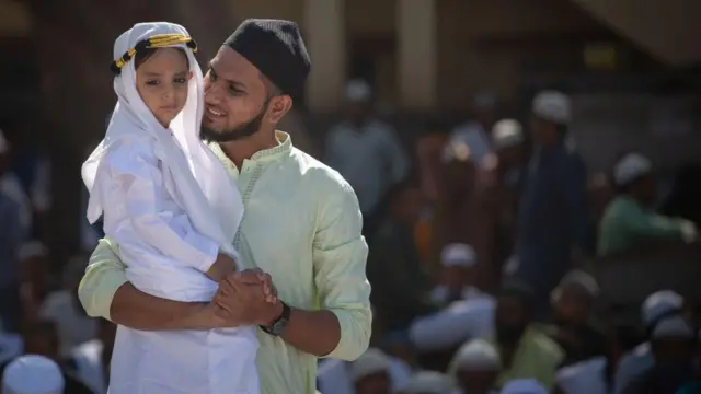 رجل يحمل طفلاً بين ذراعيه.