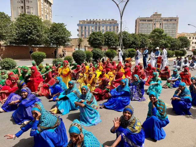ንሃገራዊ ሕብርታት (ቀይሕ፡ ሰማያዊ፡ ቀጠልያን ብጫን) ብዝውክል ኣልባሳት ዝወቀባ ደቂኣንስትዮ ኣብቲ ካርኒቫል ተሳቲፈን ነይረን