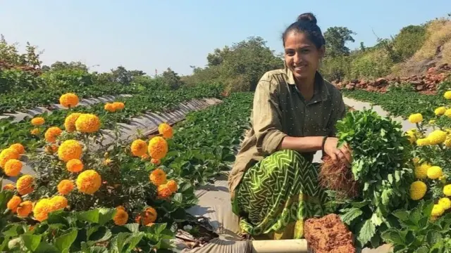 Sheetal Danavle crouches in a field, surrounded by flowers.