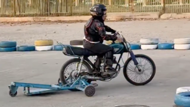 دستگاه کمکی آبی رنگ که به عقب یک موتور نصب شده تا به حفظ تعادل زن موتورسوار کمک کند