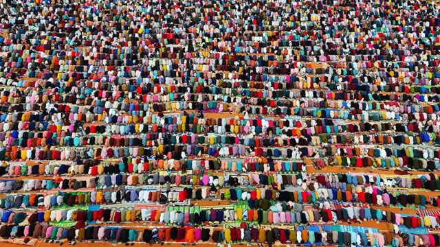 A drone view of a group of praying men bending to pray in muslim way wit different colours of clothes