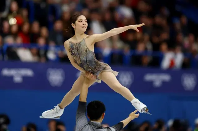 木原が左手を上に伸ばし、頭上で三浦を支えている。三浦は足を開き、左手を横に伸ばしている