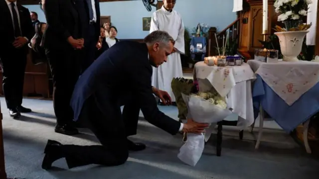 El primer ministro de Canadá, Mark Carney, se arrodilla para colocar un ramo de flores en una iglesia de Vancouver, 27 de abril de 2025