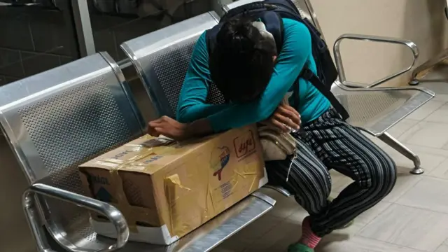 Yawa Sumpa Puar Alexandra chora sobre a caixa de papelão que contém os restos de sua bebê de um mês