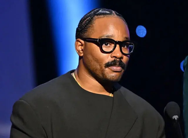Ryan Coogler, vestido de negro y con unas gafas de marco grueso negro