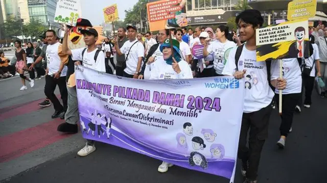 Pegiat membentangkan spanduk dan poster saat kampanye Pilkada damai 2024 di Jakarta, Minggu (17/11/2024). Kampanye Pilkada damai itu mengusung tema perempuan berani mengawasi dan memilih #BersamaLawanDiskriminasi.