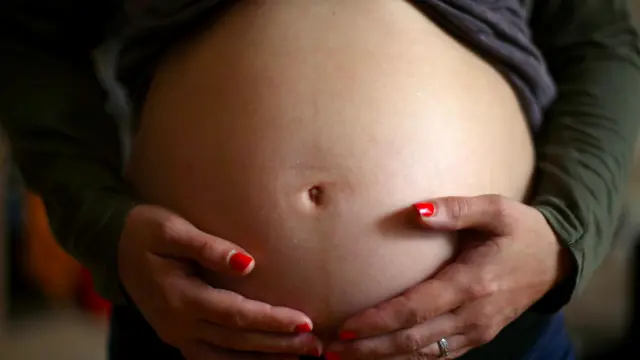 Une femme enceinte pose ses mains sur son ventre.