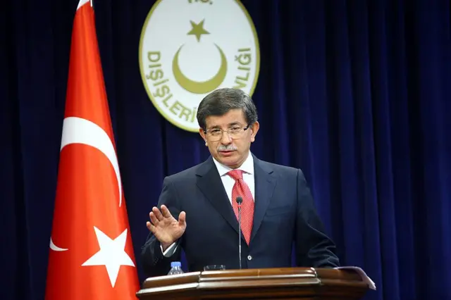 Dönemin Dışişleri Bakanı Ahmet Davutoğlu 2 Eylül 2011'de Ankara'da düzenlenen bir basın toplantısında konuşuyor. Arkasında Türk bayrağı ve dışişleri Bakanlığı logosu var.