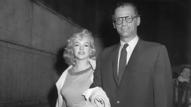 Marilyn Monroe y Arthur Miller sonríen y caminan del brazo