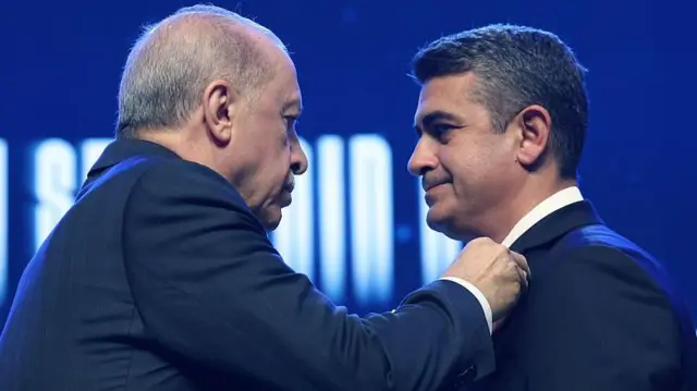 Erdoğan Levent Koç'a parti rozeti takarken.