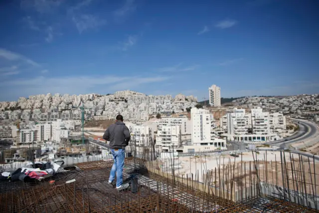 عامل فلسطيني يقف على مبنى سكني قيد الإنشاء