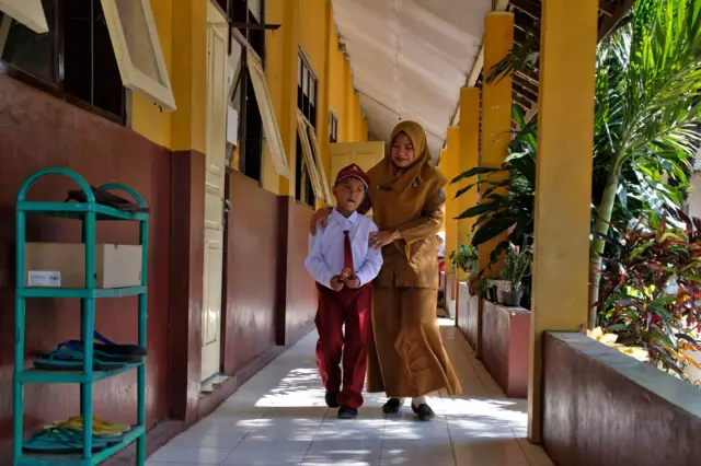 Seorang guru mengajak murid baru masuk ke kelas saat Masa Pengenalan Lingkungan Sekolah (MPLS) di SD Negeri Butuh, Temanggung, Jawa Tengah, Senin (13/7/2026). SD Negeri Butuh hanya menerima dua murid baru selama dua tahun berturut-turut, dan pada hari pertama masuk sekolah tahun pelajaran 2026/2027 hanya seorang murid yang hadir karena satu murid lainnya sakit.