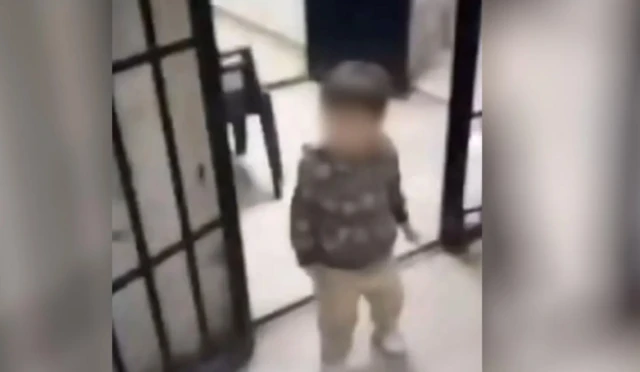 Dalam sebuah klip video, seorang anak kecil berjalan melalui pintu sel penjara Sednaya